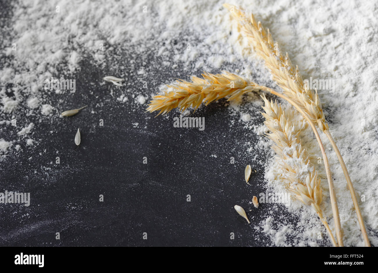 whole flour and wheat ears on black board Stock Photo