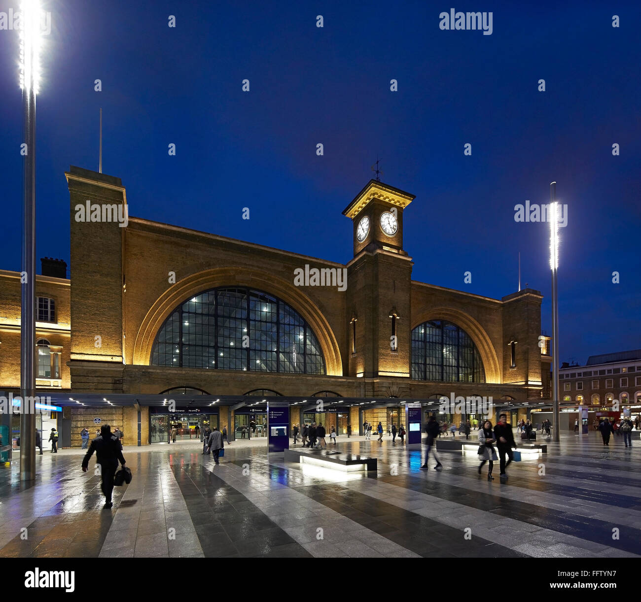 Oblique elevation of square and historic station at night. King's Cross Square, London, United Kingdom. Architect: Stanton Willi Stock Photo