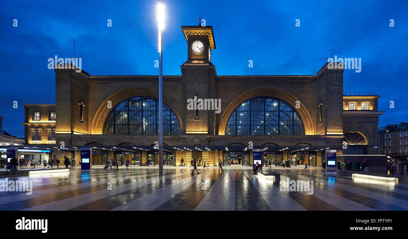 Front elevation of square and historic station at night. King's Cross Square, London, United Kingdom. Architect: Stanton William Stock Photo