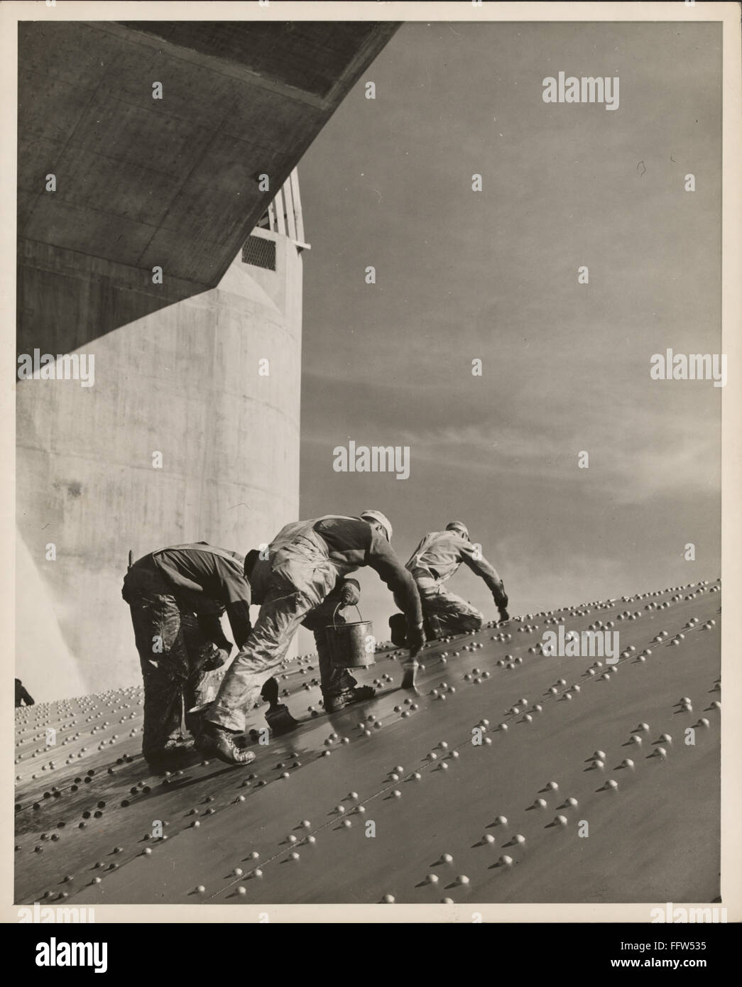 HOOVER DAM, c1940. /nThree construction workers applying a coat of paint on a riveted steel wall on the Hoover Dam spillway, c1940. Stock Photo