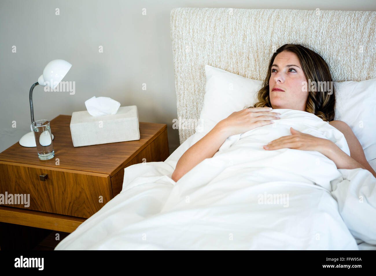 sick woman lying in bed looking unwell Stock Photo Alamy