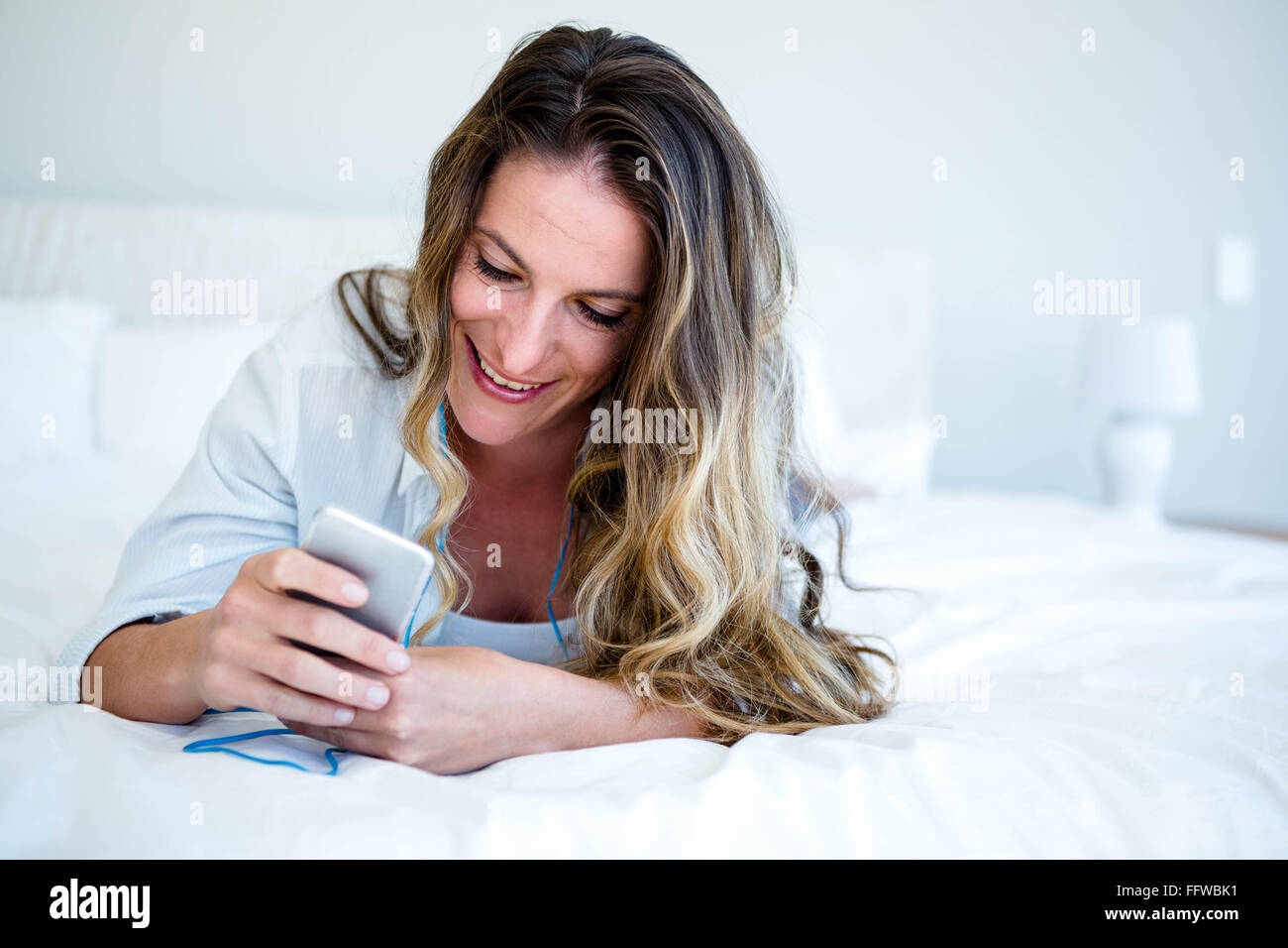 woman lying on her bed listening to music Stock Photo - Alamy