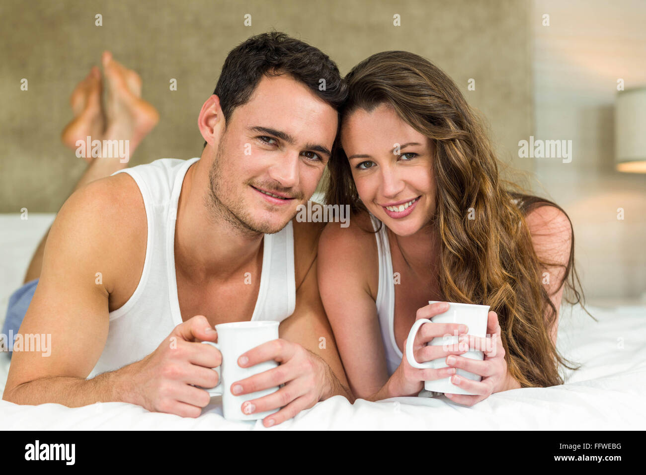 Young couple having cup of coffee on bed Stock Photo - Alamy