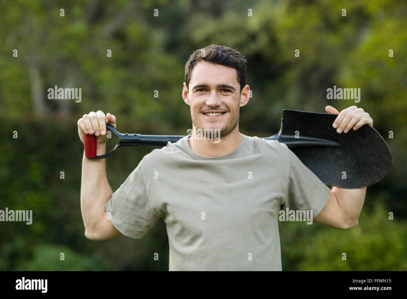 Portrait of young man standing with a gardening shovel Stock Photo - Alamy