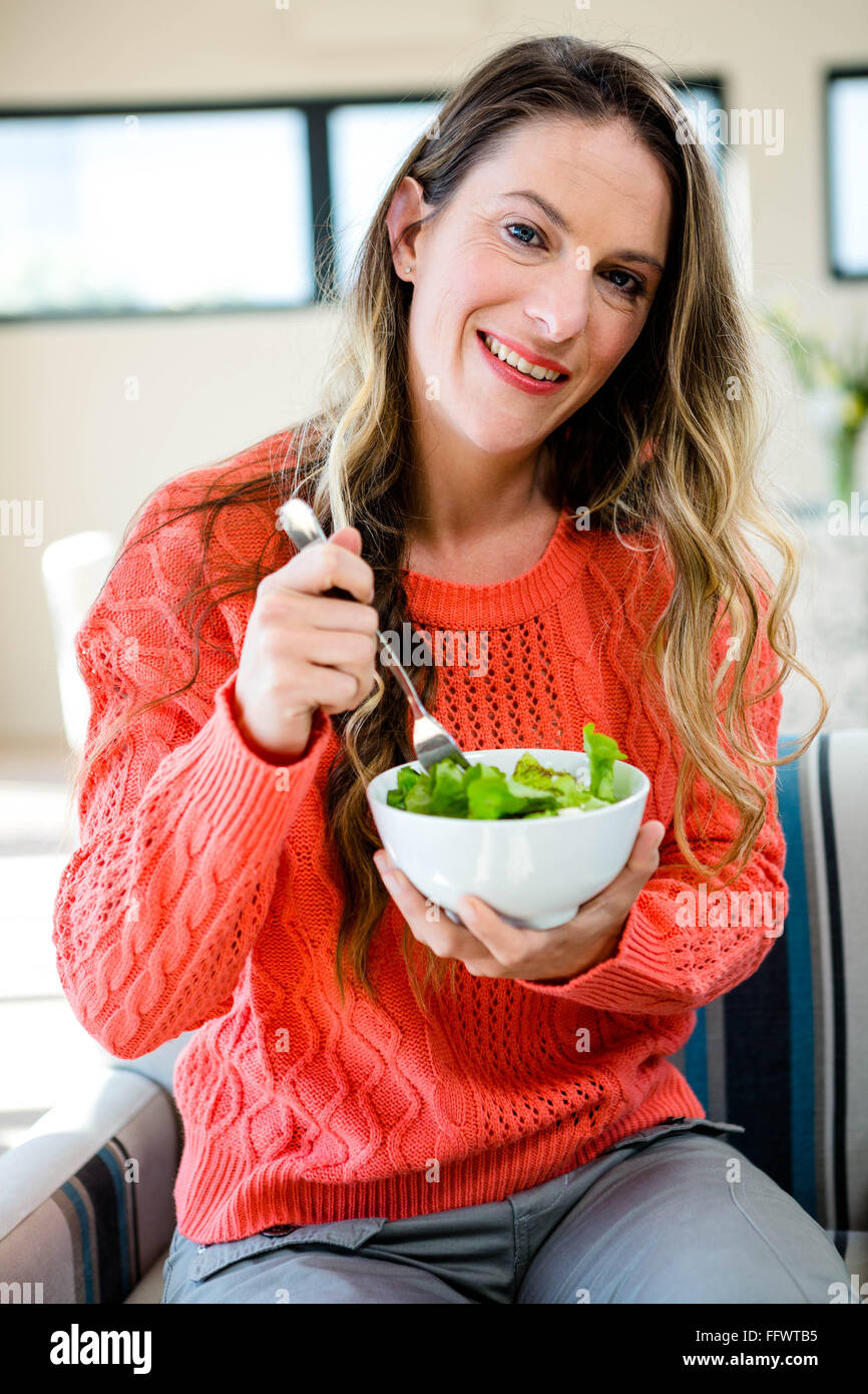 smiling woman eating a bowl of salad Stock Photo