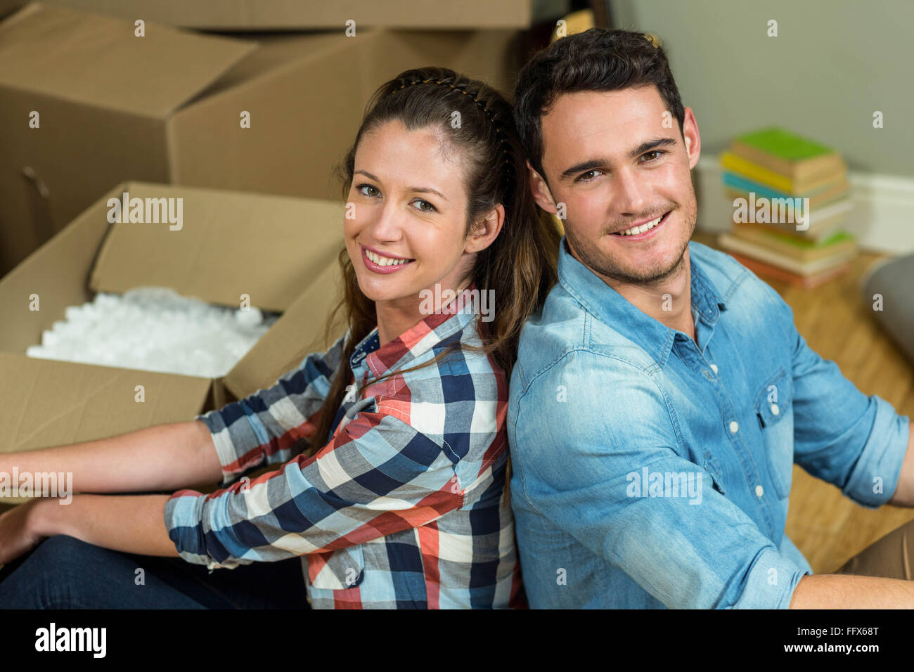Young couple sitting back to back in their new house Stock Photo