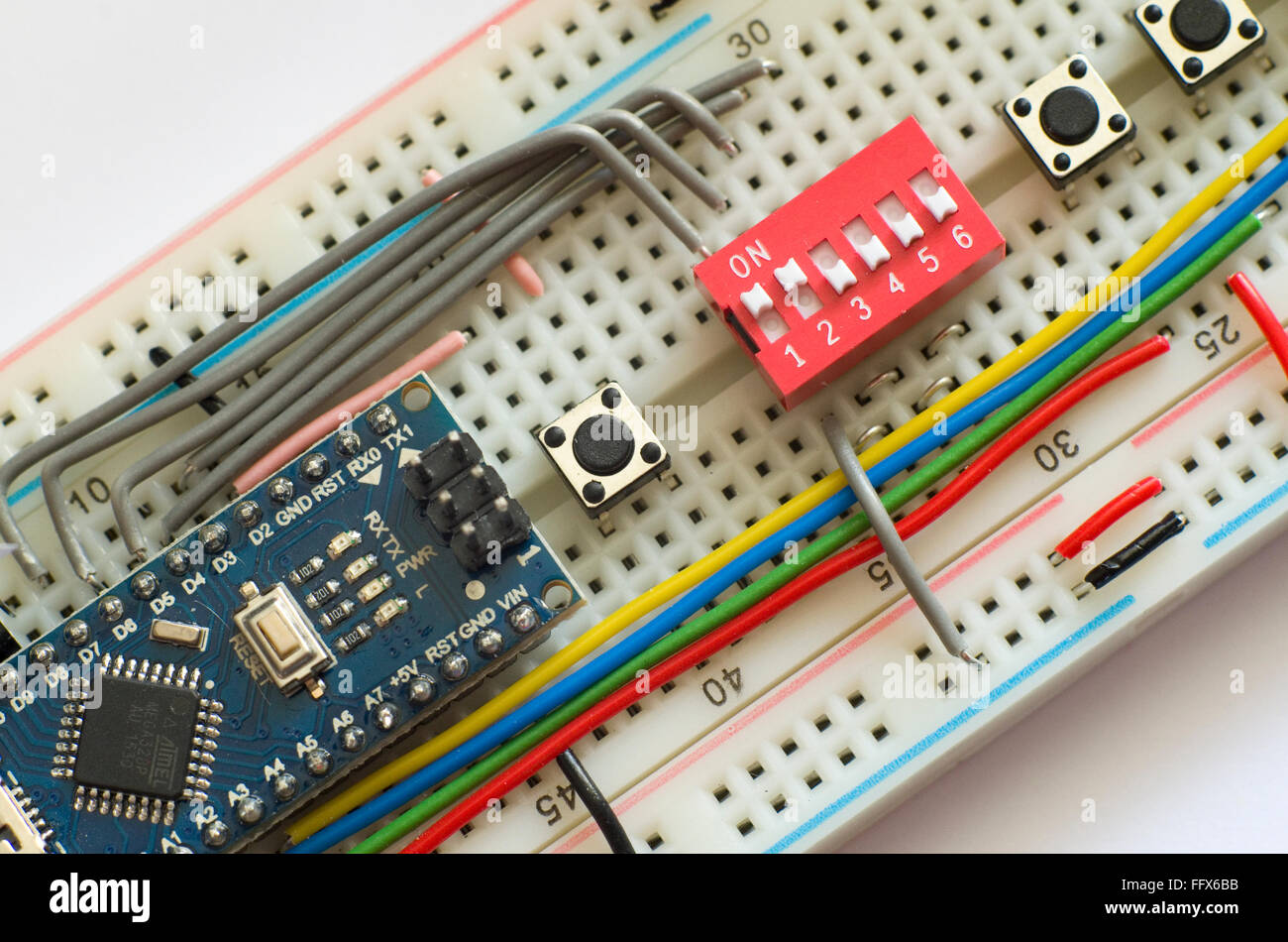 Electronics prototyping board (breadboard) with an Arduino Pro Mini clone and an assortment of switches and wires. Stock Photo