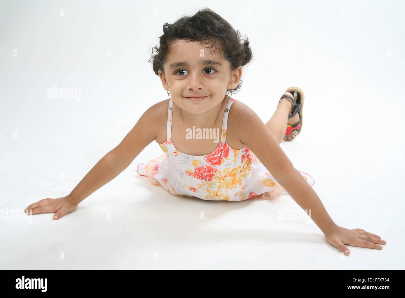 young girl of 4 years playful mood laying on ground on stomach with both hands open and smiling MR# 687D Stock Photo