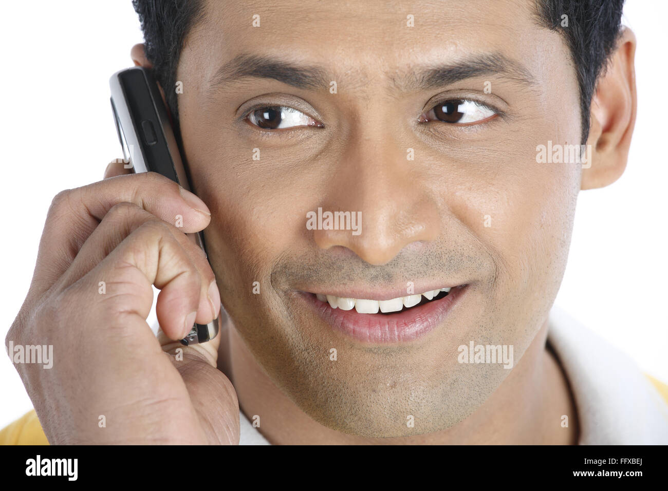 Confident young man holding mobile phone to his right ear and talking MR#703R Stock Photo