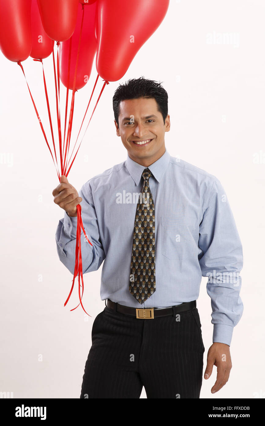 Businessman holding red coloured gas balloons in one hand MR#703T Stock Photo
