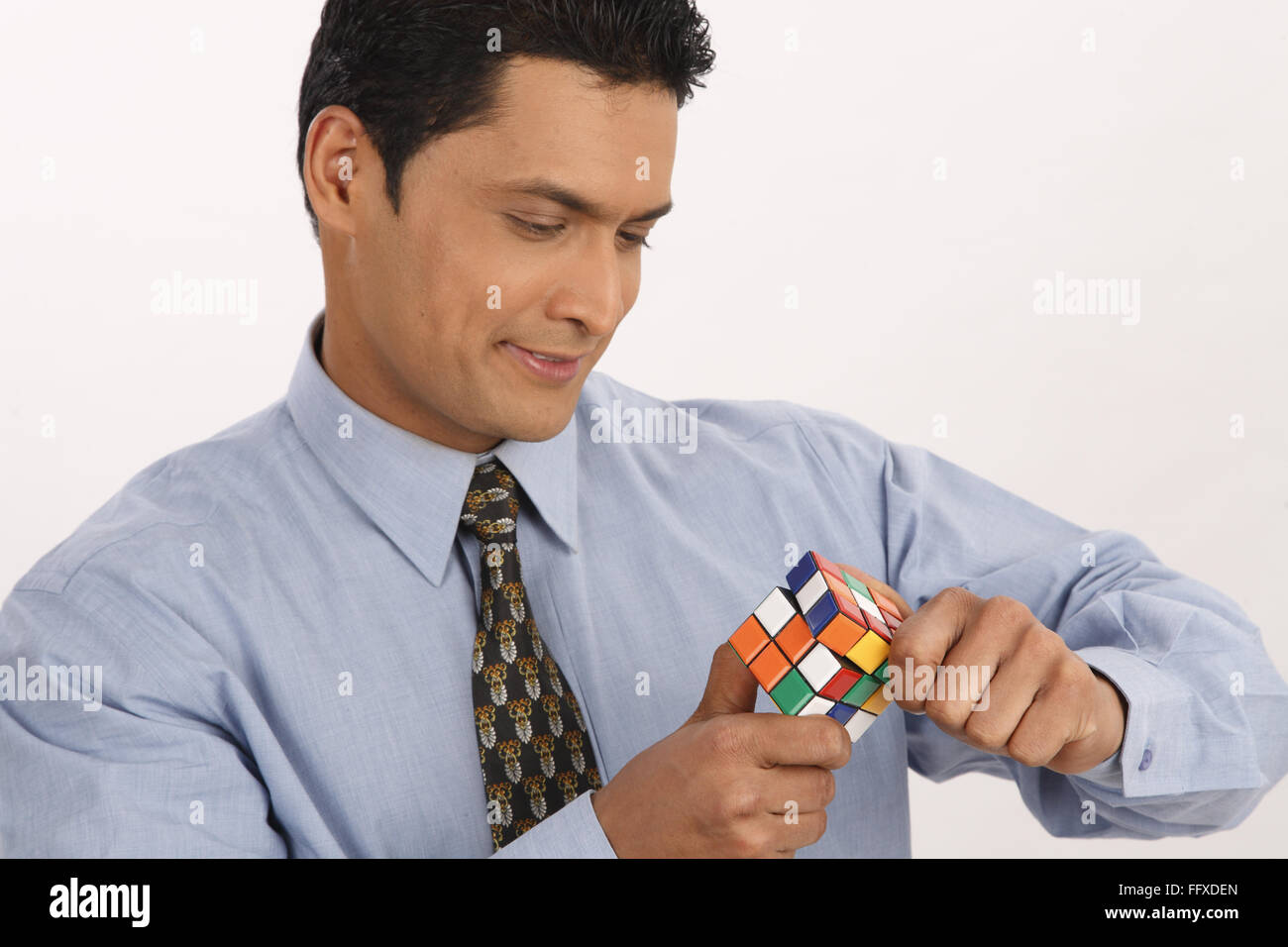 Businessman holding Rubik cube trying to solve puzzle MR#703T Stock Photo