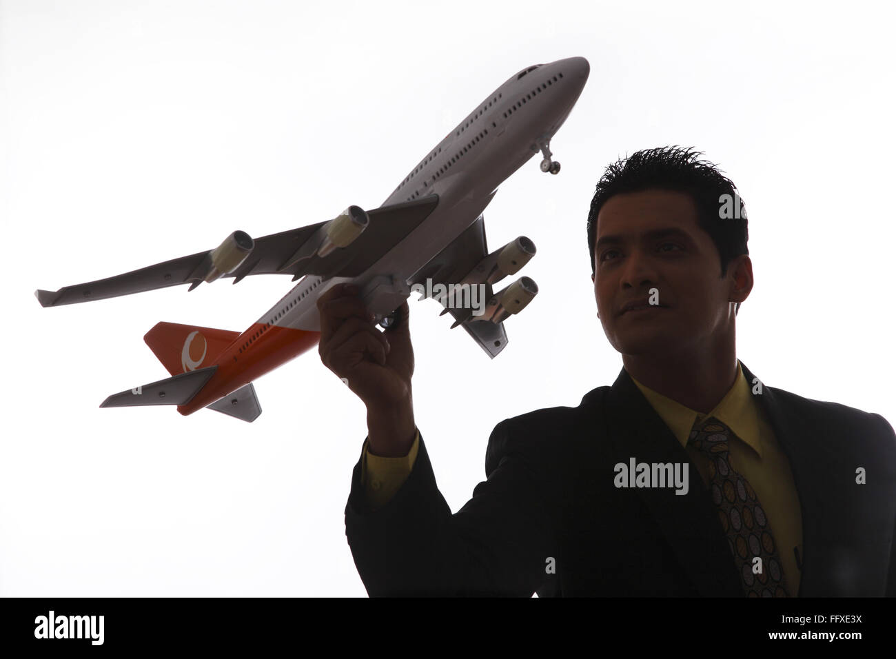 Businessman in silhouette holding passenger aeroplane in flying angle in one hand MR#703T,NO PR Stock Photo