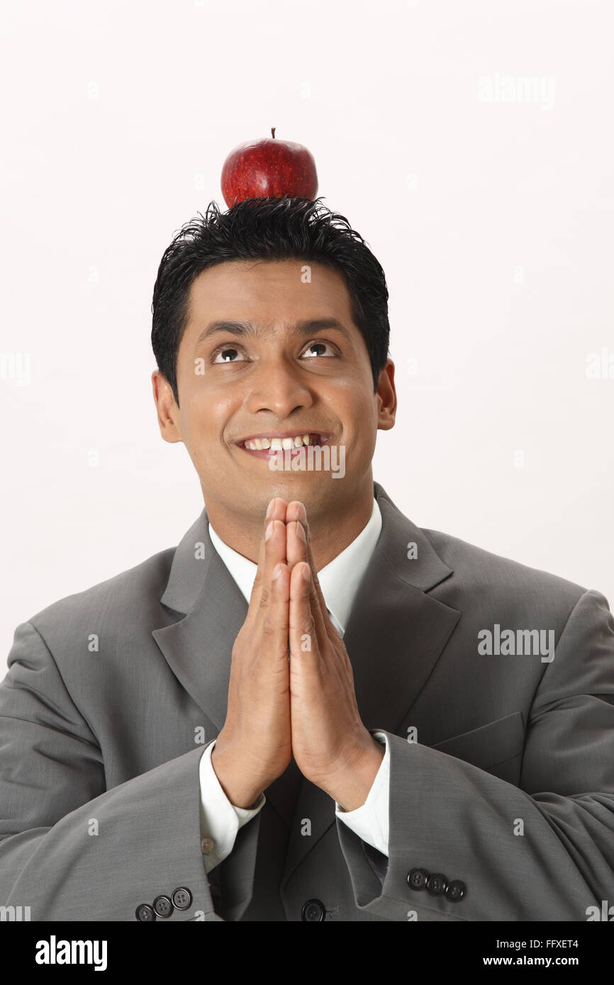 Businessman kept red apple on his head and joined both hand palms MR#703T Stock Photo
