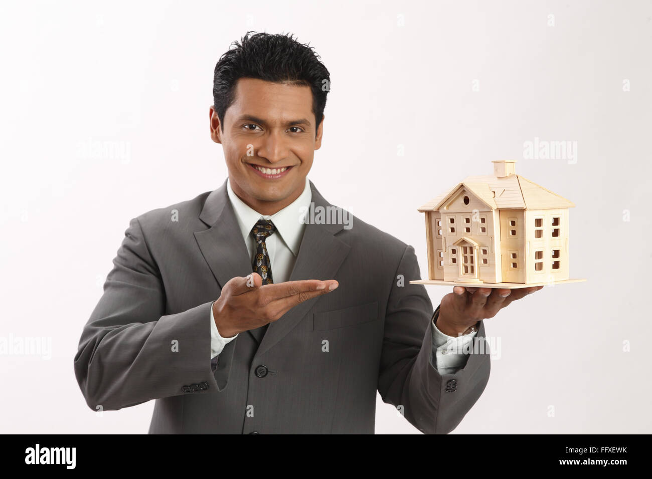 Businessman holding house model in left hand MR#703T Stock Photo - Alamy