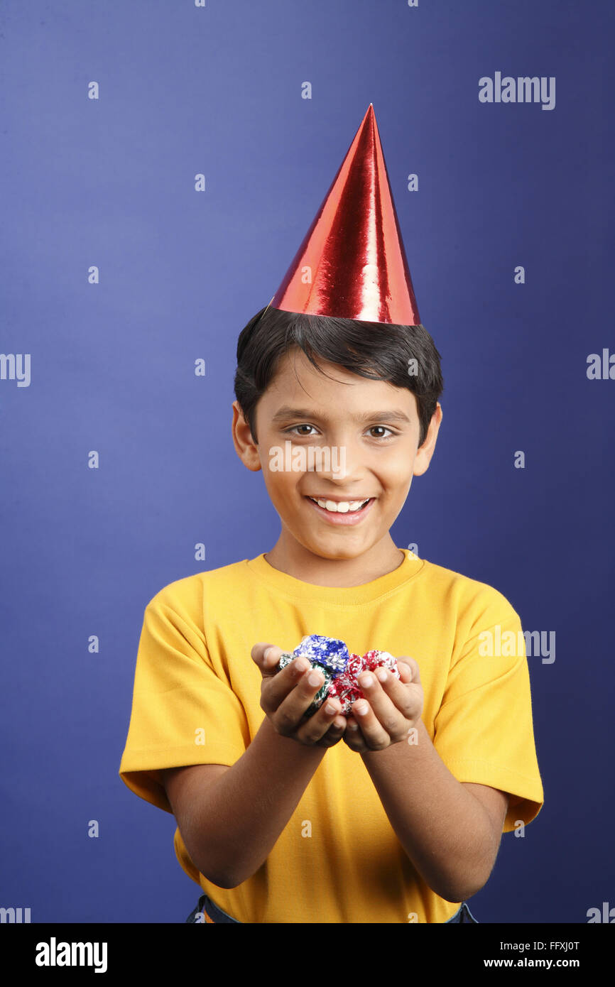 Ten year old boy holding chocolates in both hands wearing cone shaped