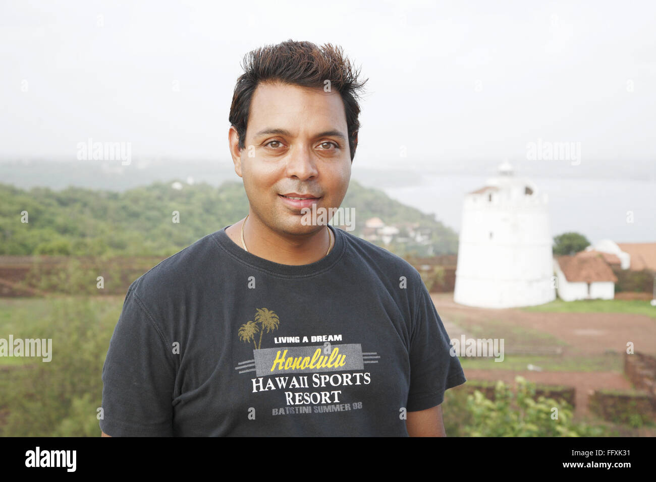 Man smiling , Lighthouse of Fort Aguada in background , Goa , India MR#468 Stock Photo