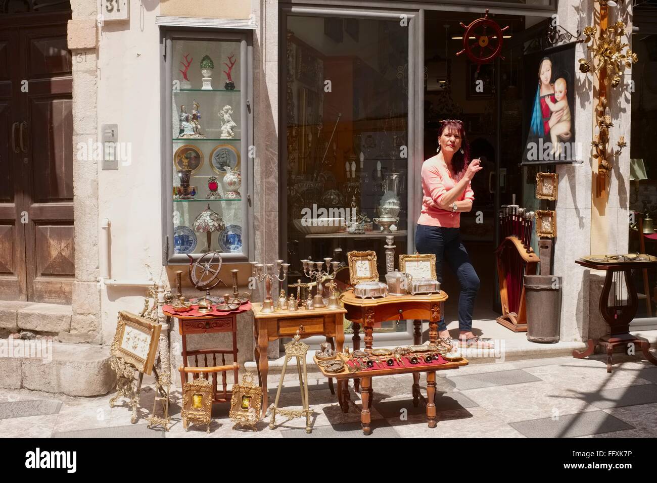 tobacco shop taormina A lady shop keeper smokes a cigarette whilst waiting for customers to he  antique shop just off the high street in Taormina, Sici Stock Photo