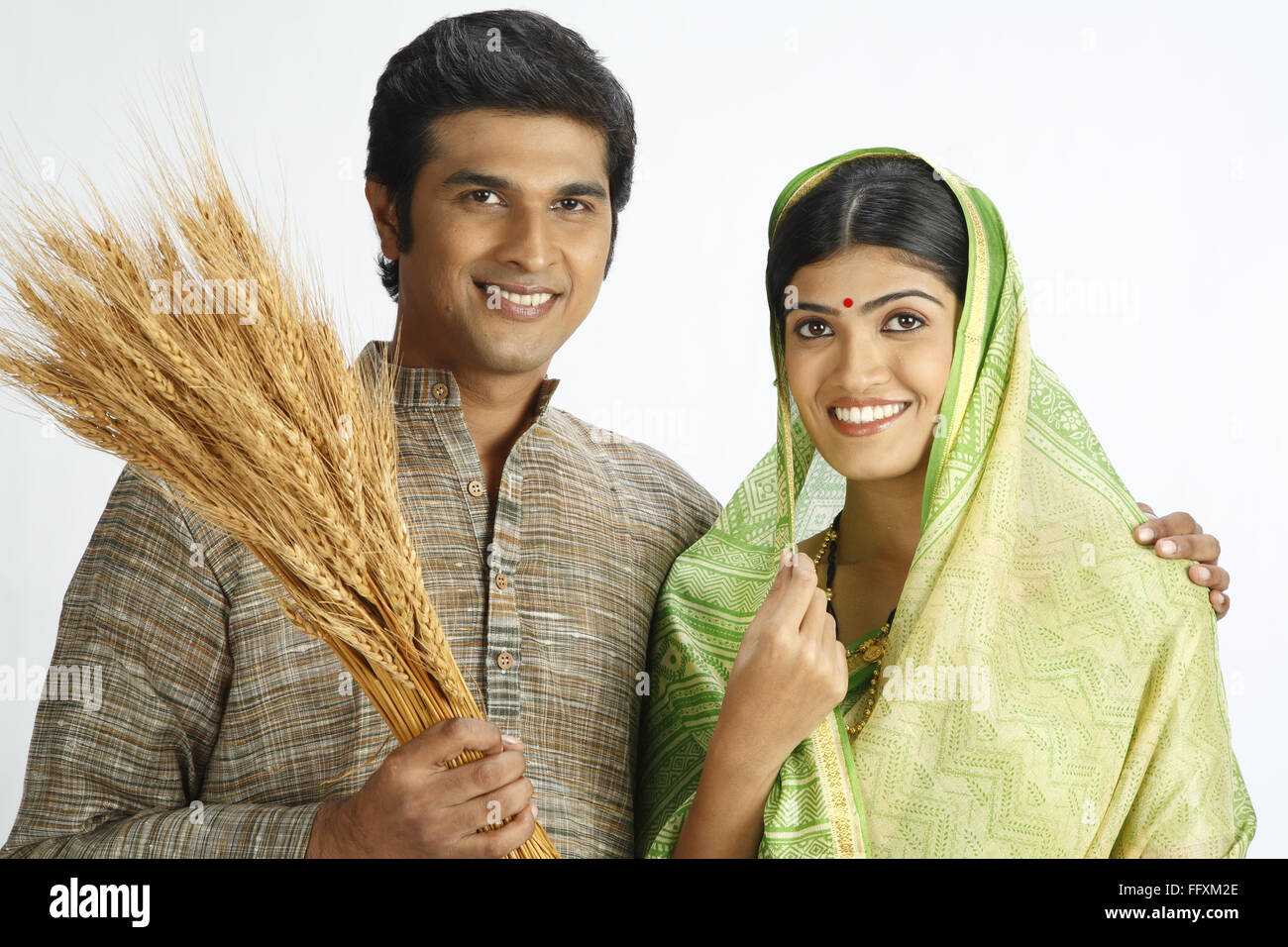 Rich Indian farmer and his wife holding harvested golden wheat crops MR#743A,743B Stock Photo