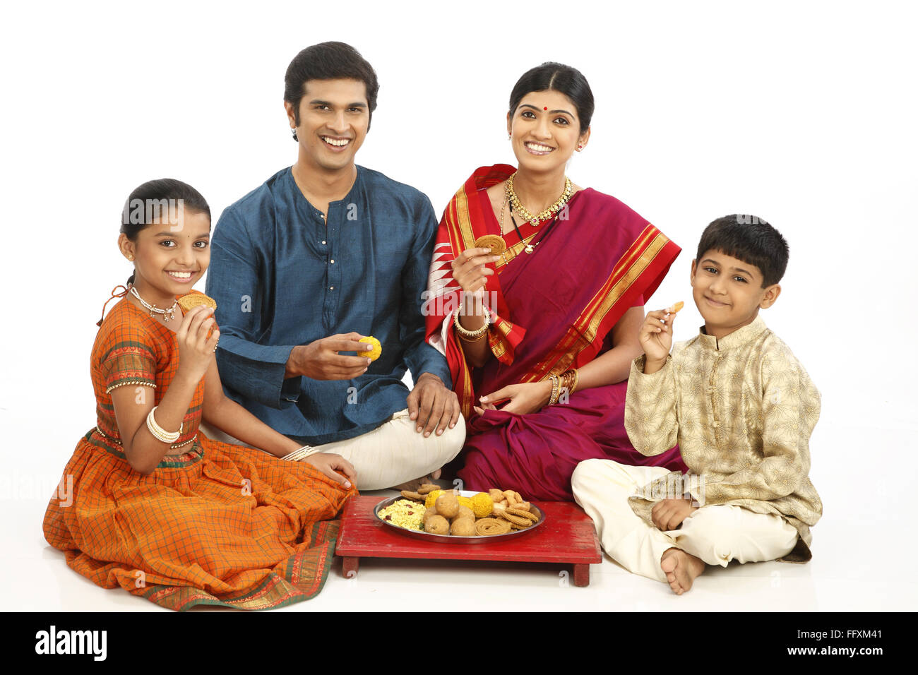 Rich rural farmer family sitting together with snacks kept in plate on wooden seat MR#743A,743B,743C,743D Stock Photo