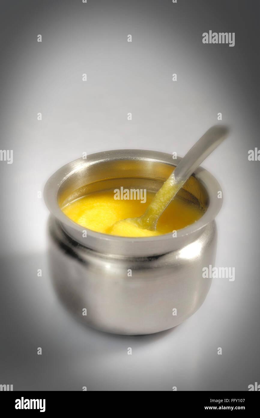 Food , pure cow ghee in steel pot with spoon on white background Stock