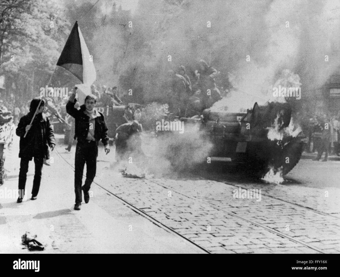 CZECH PROTEST, 1968. /nDefiant young Czechs carrying their country's flag past a burning Soviet tank on a street in Prague, in protest of the Soviet-led Warsaw Pact invasion of Czechoslovakia, 21 August 1968. Stock Photo