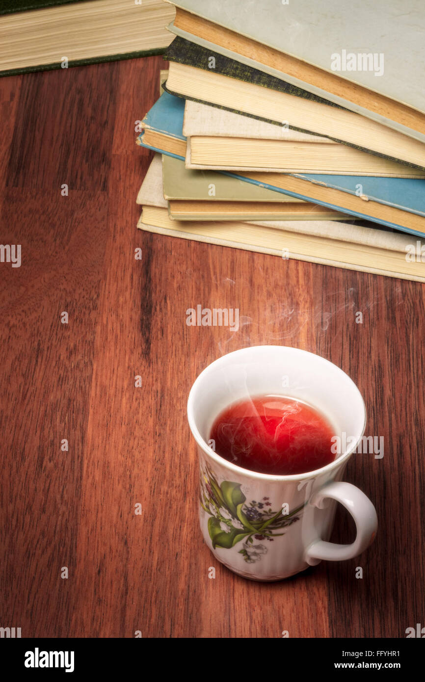Cup of tea standing next to stack of old books Stock Photo Alamy