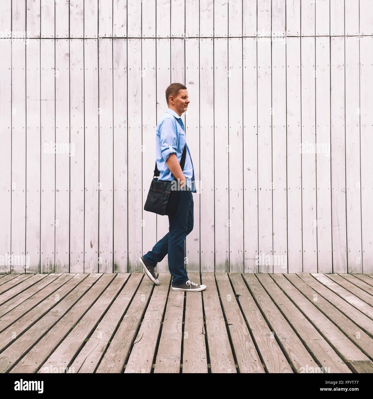 Side View Of Man Walking Against Wall Stock Photo