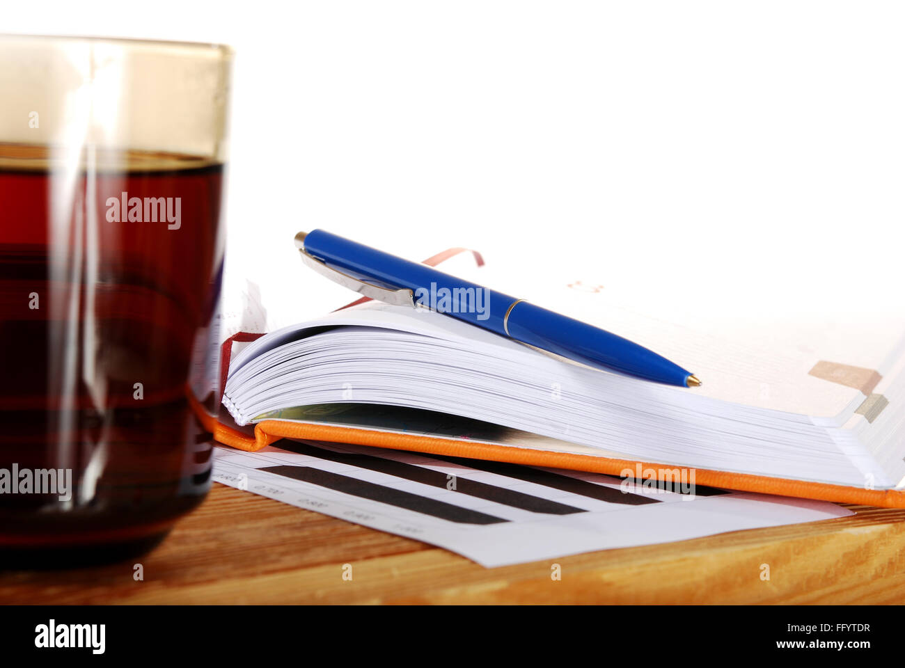 The cup of tea on a wooden table with a notebook and pen Stock Photo