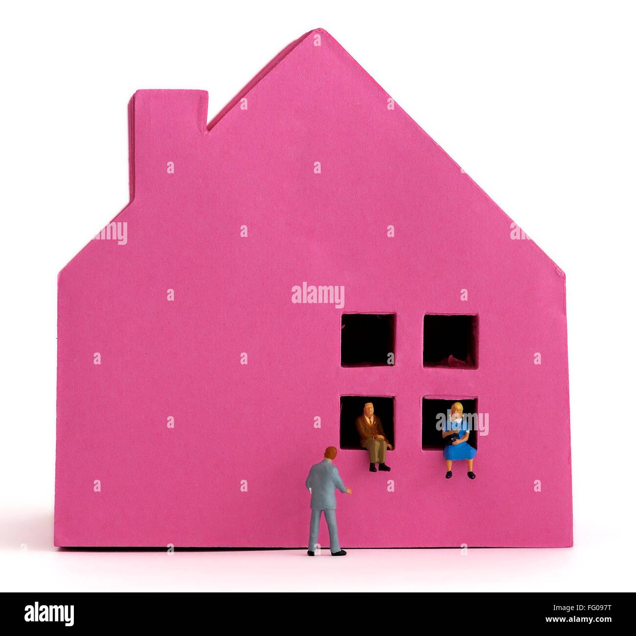 A pink paper house and a couple sitting in the windows with an estate agent in a suit. house buying concept. Stock Photo