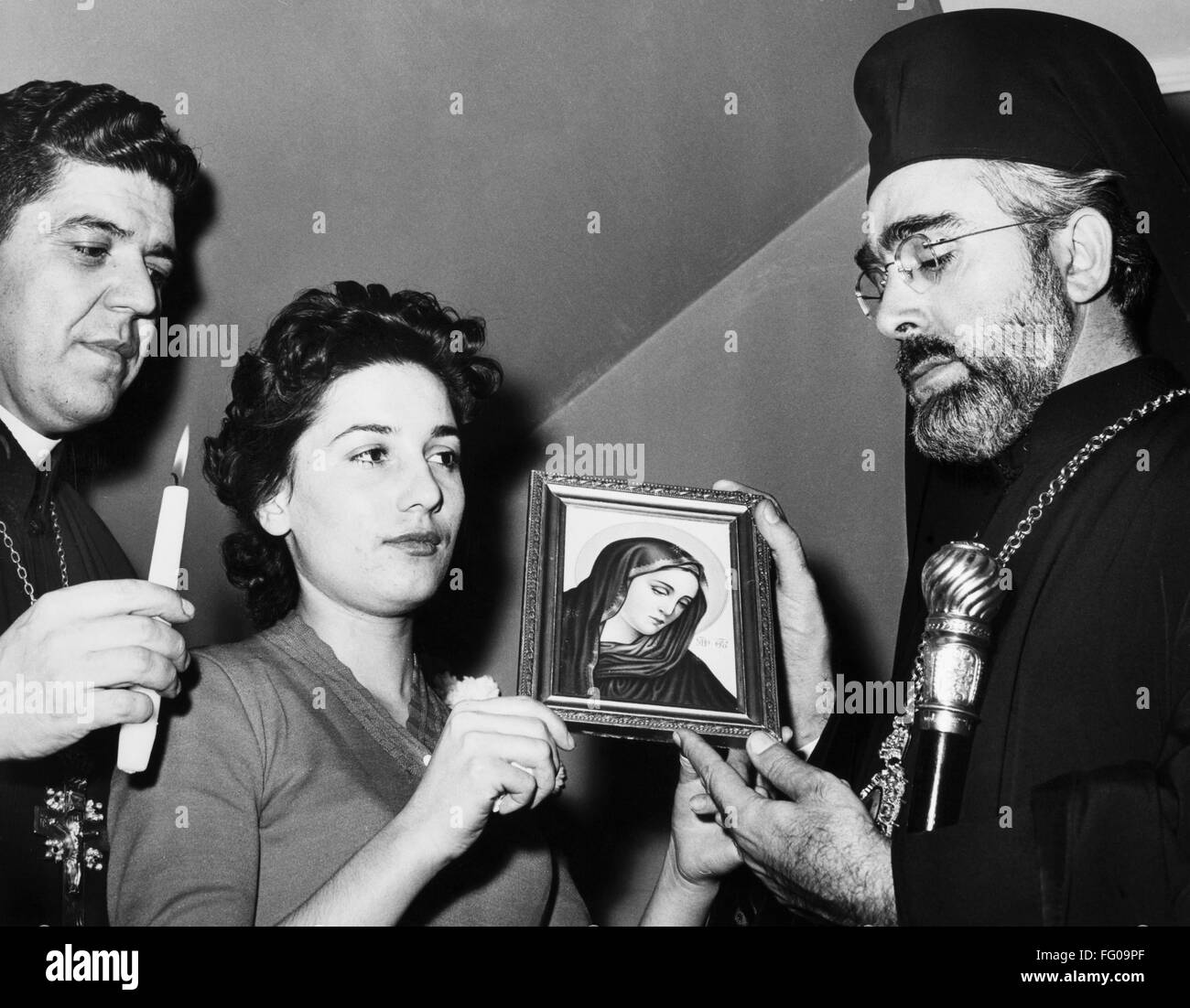ARCHBISHOP IAKOVOS /n(1911-2005). Born Demetrios Koukouzis. Primate of the Greek Orthodox Archdiocese of North and South America. Iakovos at the home of Pagora Catsouni of Long Island, New York, examining a picture of the Virgin Mary which she claims shed Stock Photo