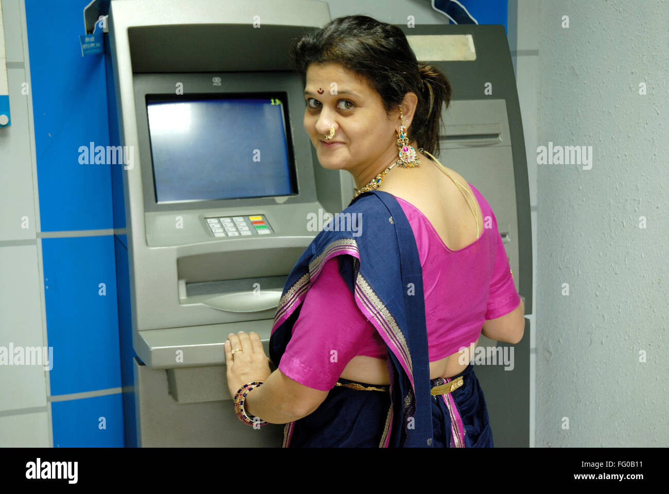 Lady using ATM card for withdraw cash from savings account at Maim , Bombay Mumbai , Maharashtra , India MR#721S Stock Photo