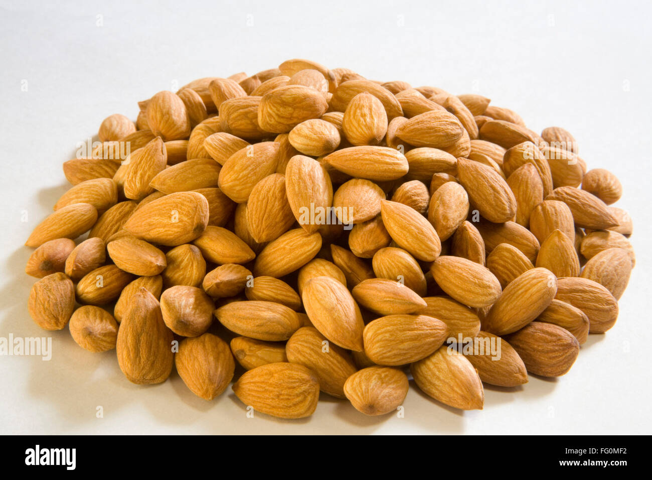 Almonds whole nuts almond heap pile Badam Prunus dulcis on white background Stock Photo