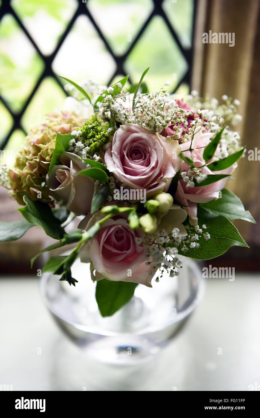 A pretty bouquet of pink roses in a small vase at a wedding Stock Photo