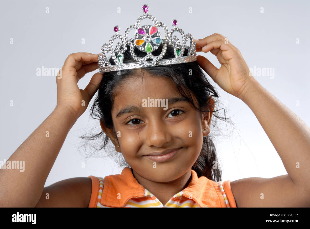South Asian Indian girl putting crown on head and smiling MR152 Stock
