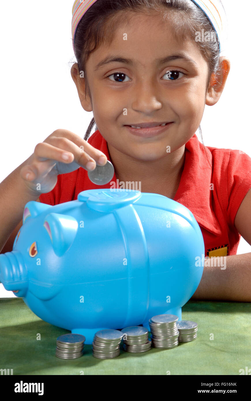 South Asian Indian six years old girl saving coins in piggy bank MR#364 Stock Photo