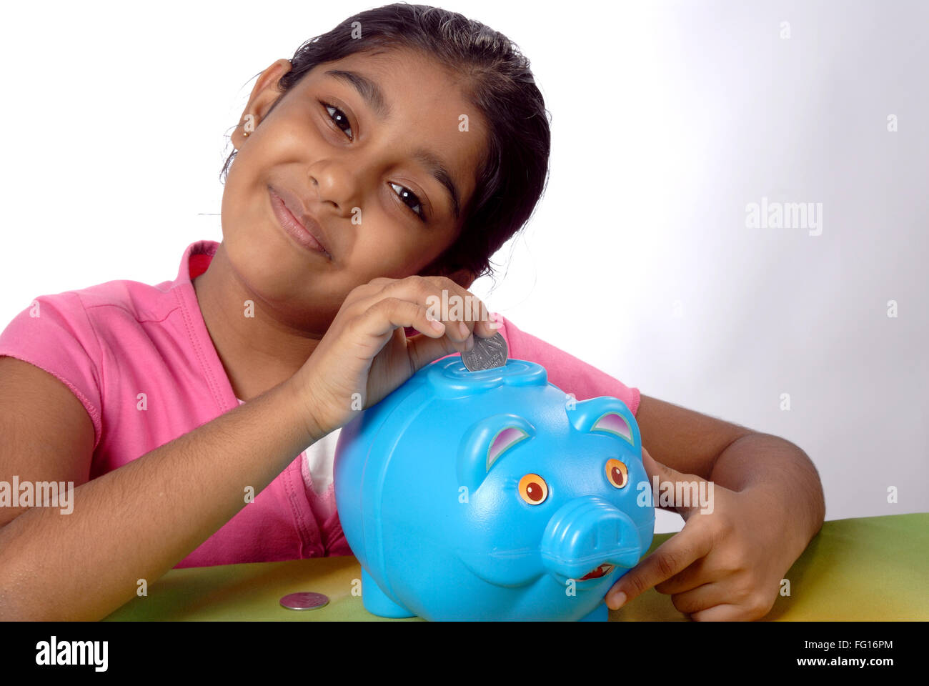 South Asian Indian year six old girl saving coins in piggy bank MR#152 Stock Photo