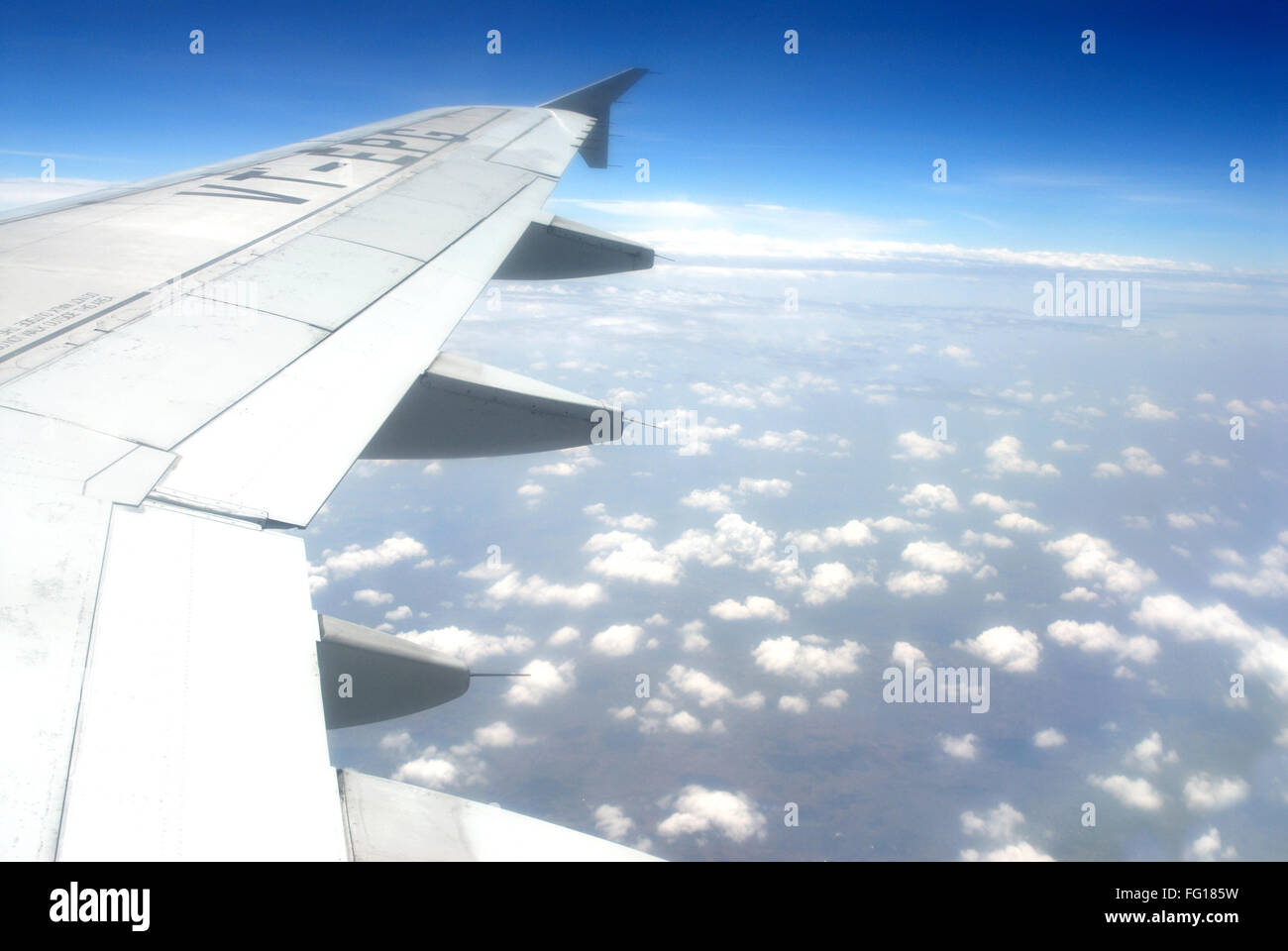 View of cloud in blue sky and wing of plane from aeroplane window Stock Photo