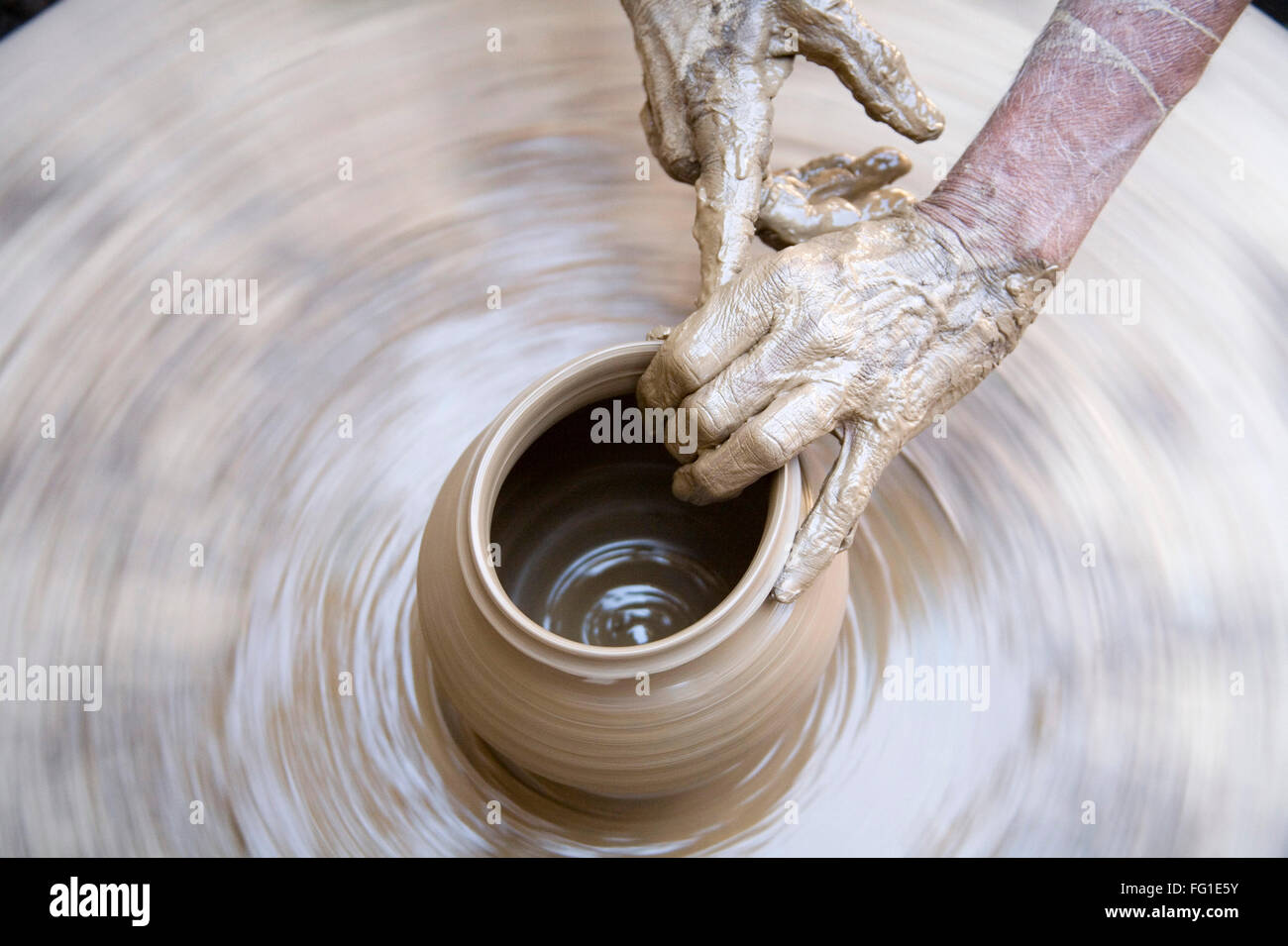 Pottery , potter artist muddy hands making clay pot giving shape on spinning wheel , Dilwara , Udaipur , Rajasthan , India , Asia Stock Photo