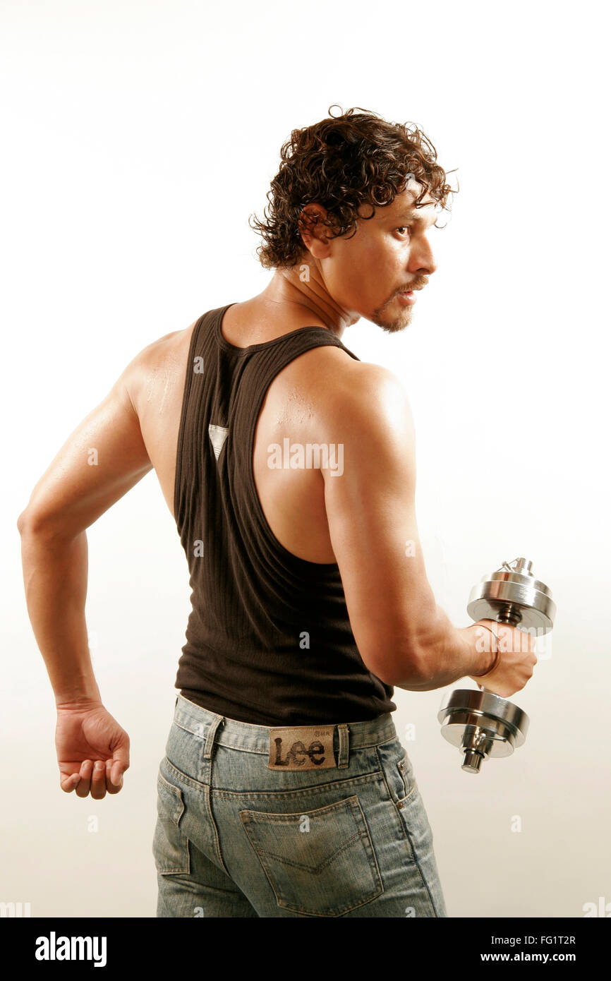 South Asian Indian man wearing black vest and curly oily hair building arms  muscles with steel dumbbell MR#686H Stock Photo - Alamy