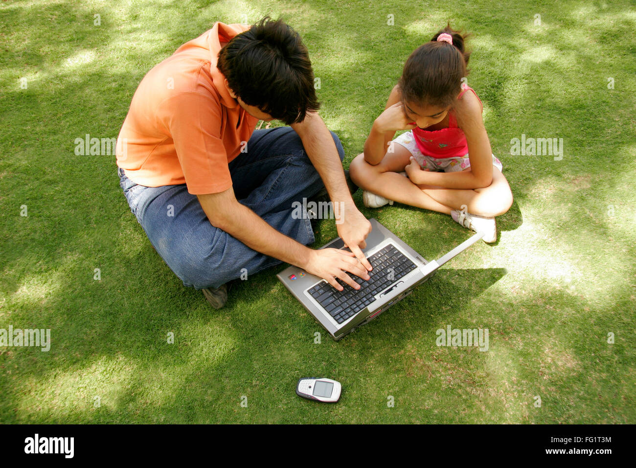South Asian Indian elder brother educating to younger sister about operation of laptop MR#686C,191 Stock Photo