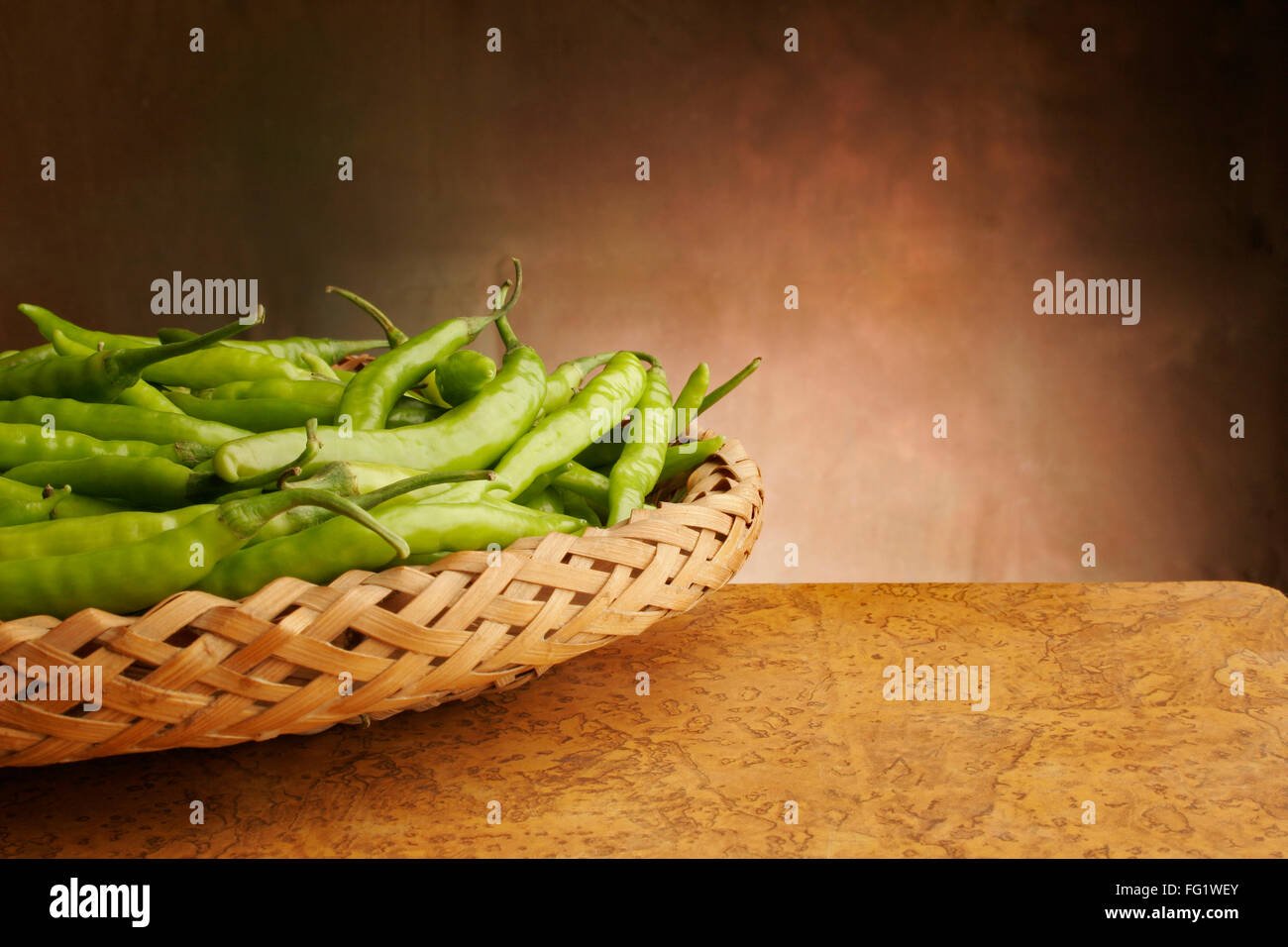 Green chillies or pepper vegetable condiment pungent in taste kept in cane basket , Pune , Maharashtra , India Stock Photo