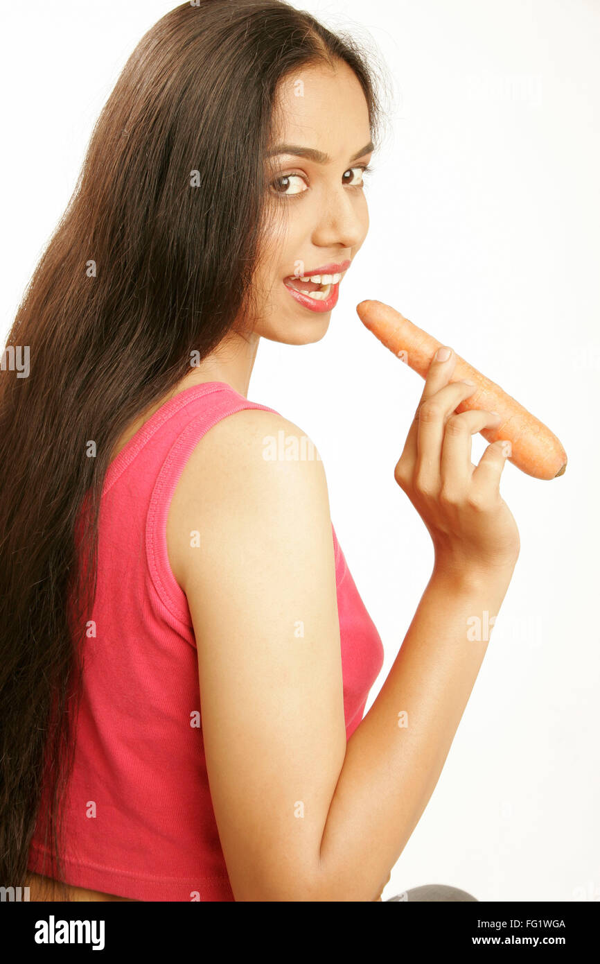 South Asian Indian teenage girl with loose black thick and long hair about  to bite raw carrot vegetable good for health Stock Photo - Alamy