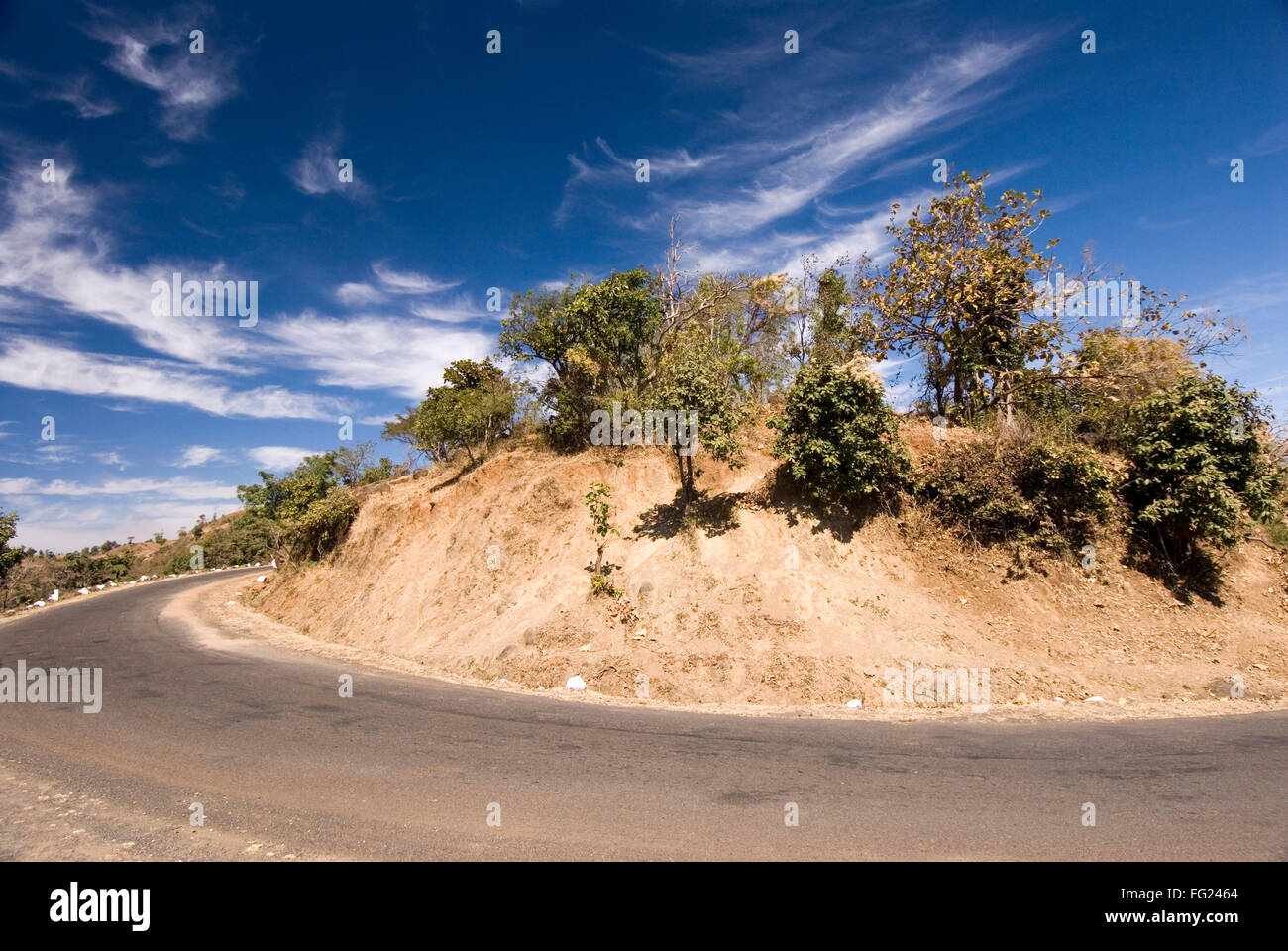 Curved road and white clouds on dark blue sky in landscape at Chikhaldara ; district Amravati ; Maharashtra ; India Stock Photo
