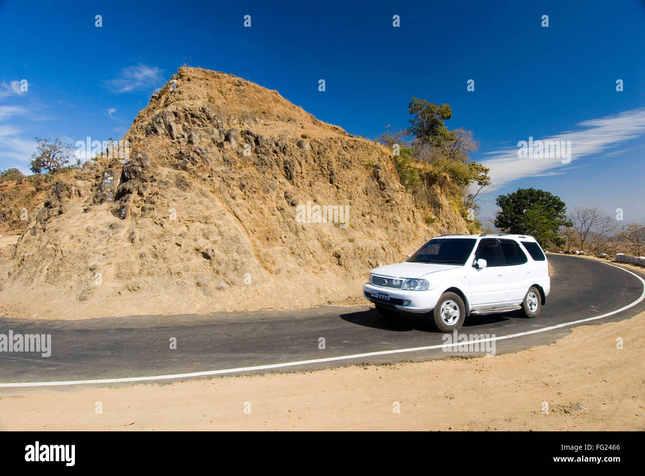 Car on curved road and white clouds on dark blue sky in landscape at Chikhaldara ; district Amravati ; Maharashtra ; India Stock Photo