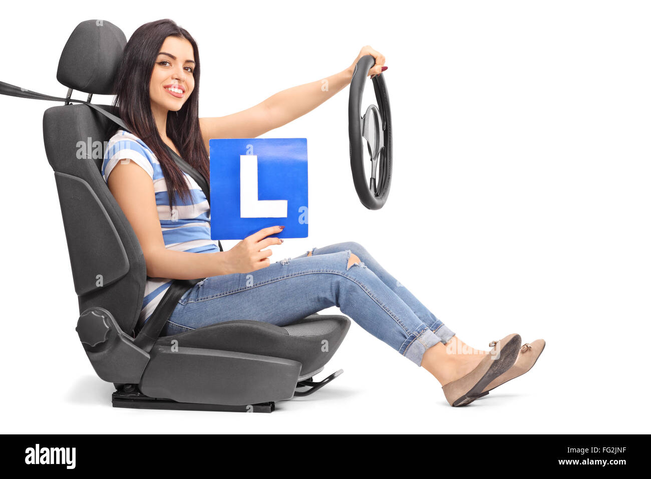 Young woman holding an L sign and a steering wheel seated on a car seat isolated on white background Stock Photo