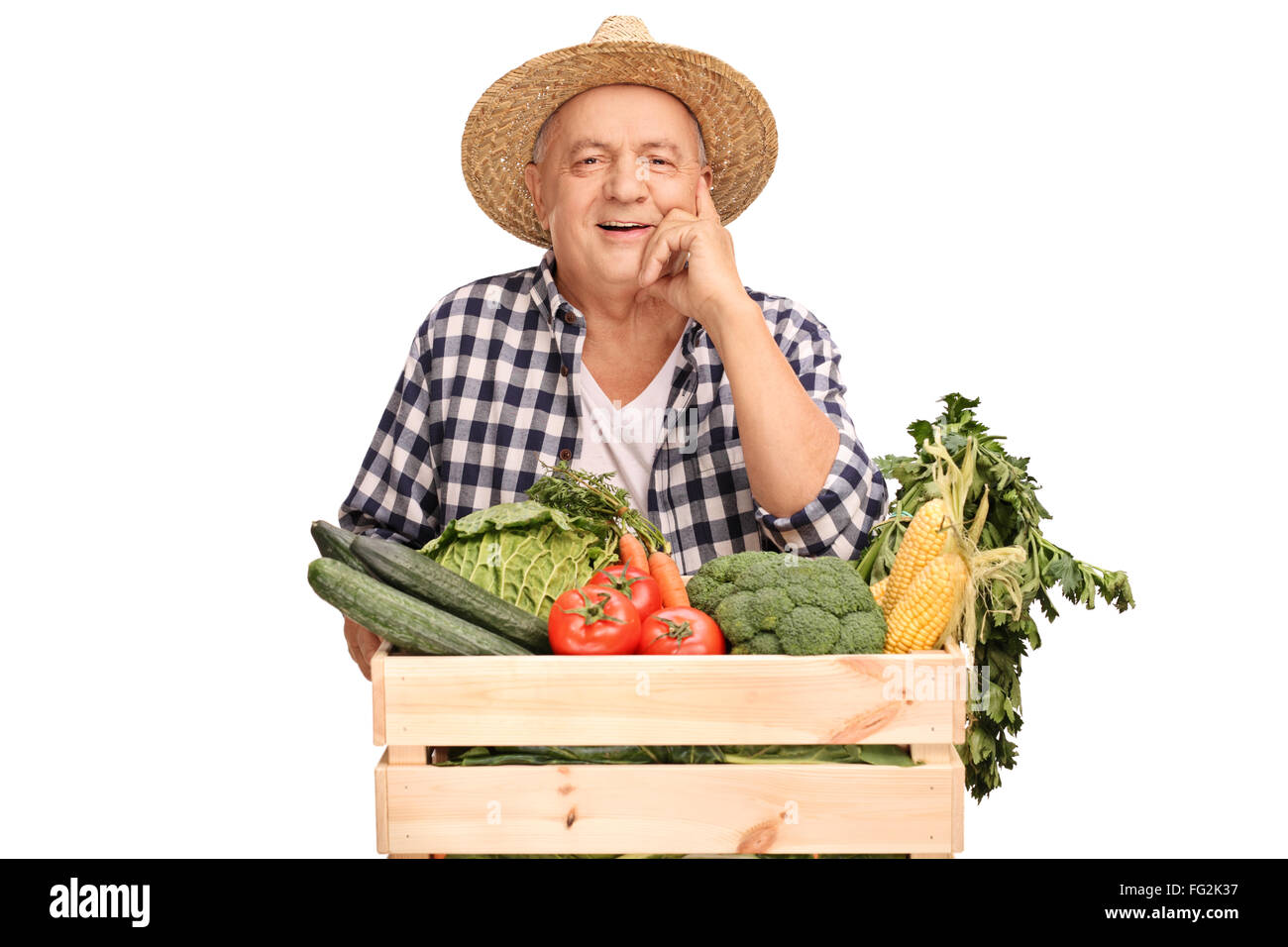 Mature agricultural worker posing behind a crate full of fresh ...