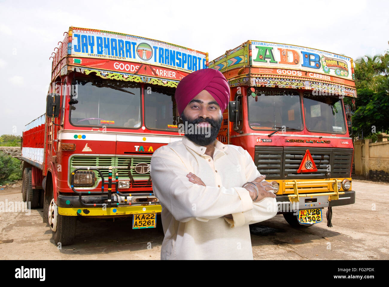 Sikh man cross hands standing in front of lorries MR#779A Stock Photo