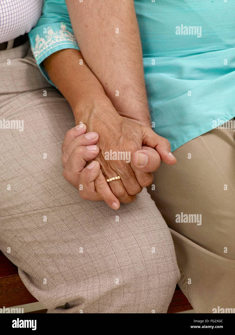 Old couple holding hands sitting close to each other MR#702T,702S Stock Photo