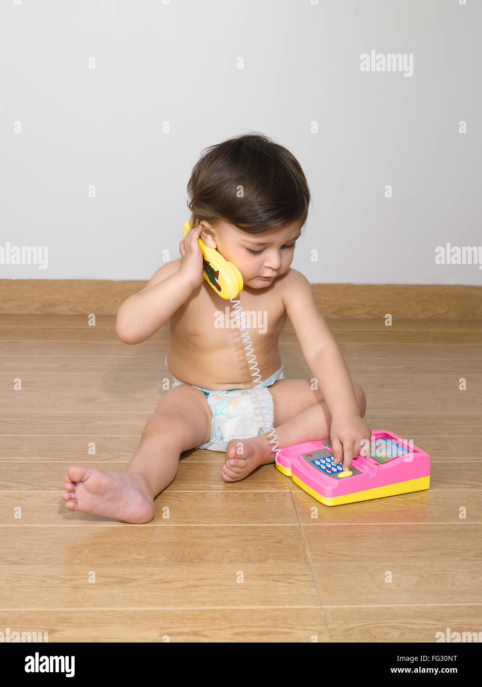 Baby wearing diaper playing with telephone set ; MR#779N Stock Photo