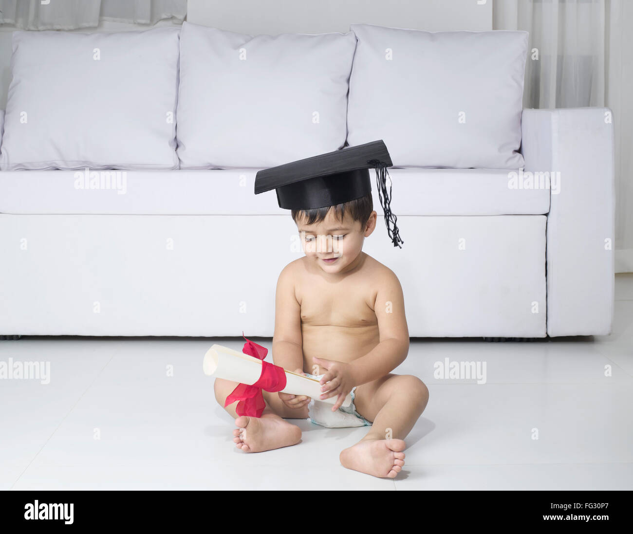 Baby wearing diaper graduation cap holding graduate degree certificate fancy dress costume MR#779O Stock Photo